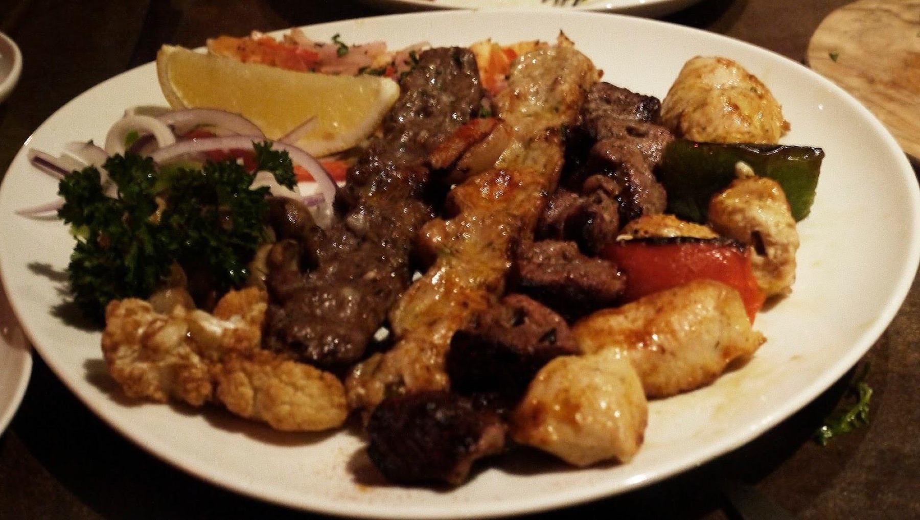Piatto misto di carne alla griglia servito su un tavolo apparecchiato.